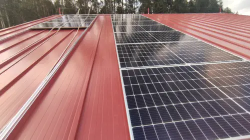 Instalación fotovoltaica sobre cubierta metálica roja, con la estructura y el cableado vistos