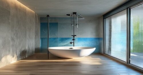 A modern bathroom with a floating wooden floor (tarima flotante) and a glass shower enclosure with blue-tinted panels. The walls are made of plasterboard (yeso laminado) with waterproof tiles. The sho