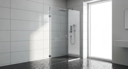 A realistic photo of a bathroom with porcelain tile floor and a frameless glass shower enclosure being installed. A worker is drilling into the wall, not the floor, with a diamond-tipped drill bit. Th