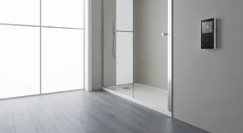 A small modern bathroom with a walk-in shower, a frameless glass shower screen, luxury vinyl plank flooring, and underfloor heating thermostat on the wall. Realistic, bright, clean, no text.