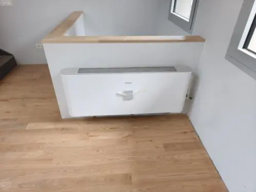Fancoil de consola instalado a nivel de suelo en una vivienda, en el lugar que ocupaba el radiador