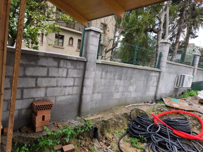Unidad exterior de aire acondicionado instalada sobre el muro de cierre de una vivienda