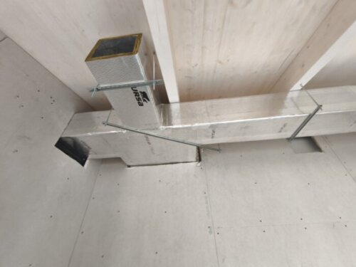 Red de conductos de fibra con plenums y rejillas colgada del techo en una instalación de climatización