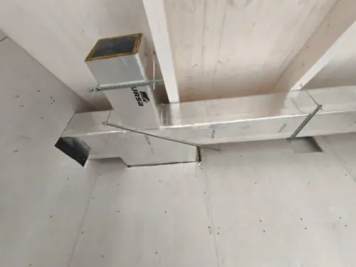 Red de conductos de fibra con plenums y rejillas colgada del techo en una instalación de climatización