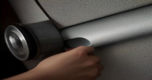 Close-up of a person's hands wrapping a plumbing pipe inside a drywall partition with acoustic mineral wool and aluminum tape, tools visible, realistic lighting, construction site background.