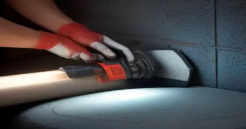 Close-up of a worker using an angle grinder with diamond disc to cut a groove in a tiled brick wall, with protective tape on tiles, dust extraction visible, realistic lighting.